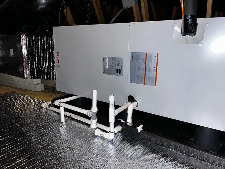 A white box with pipes attached to it is sitting on top of a foil covered floor.