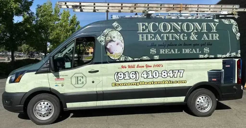 A economy heating and air van is parked in a parking lot.