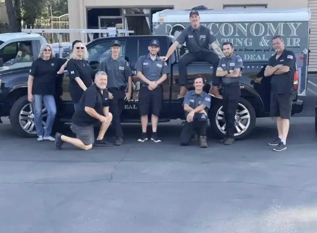 A group of people posing for a picture in front of a truck that says economy heating and cooling