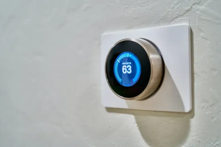 A smart thermostat is sitting on a white wall.