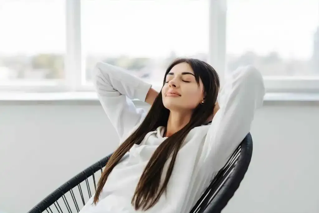A woman is sitting in a chair with her eyes closed.