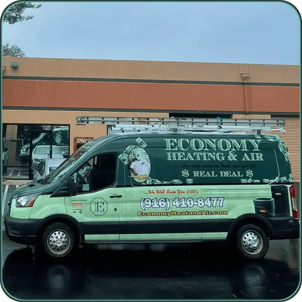 A green economy heating and air van is parked in front of a building