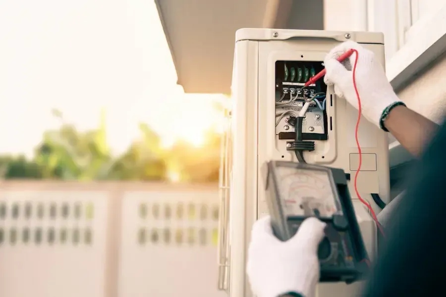 A man is using a multimeter to test an air conditioner.