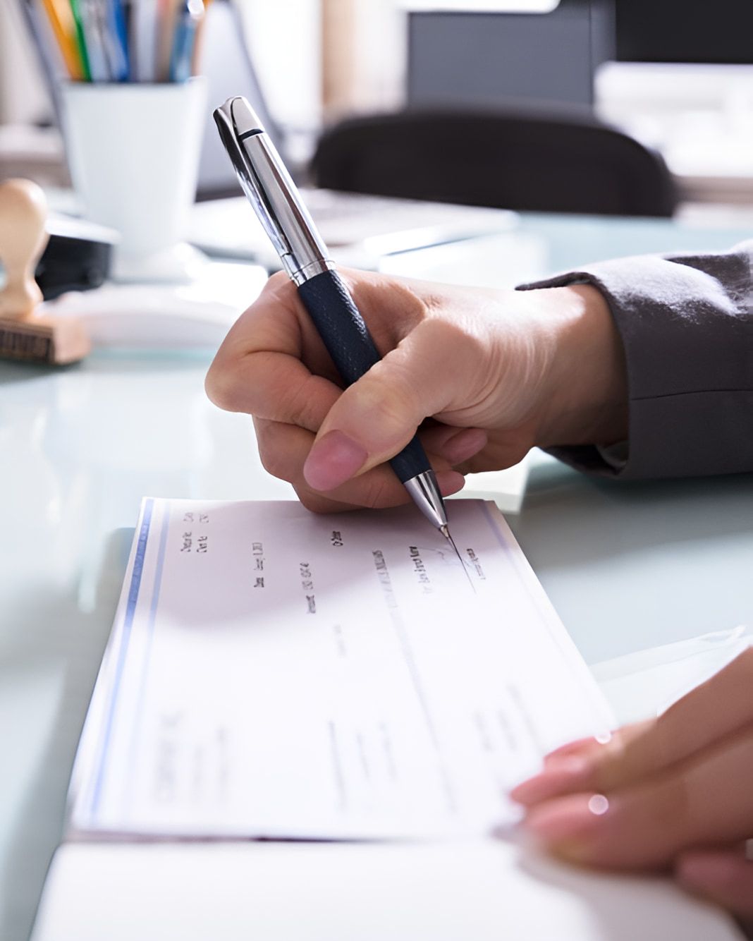 A Person is Writing a Check With a Pen — AJA Bookkeeping Services In Cairns, QLD