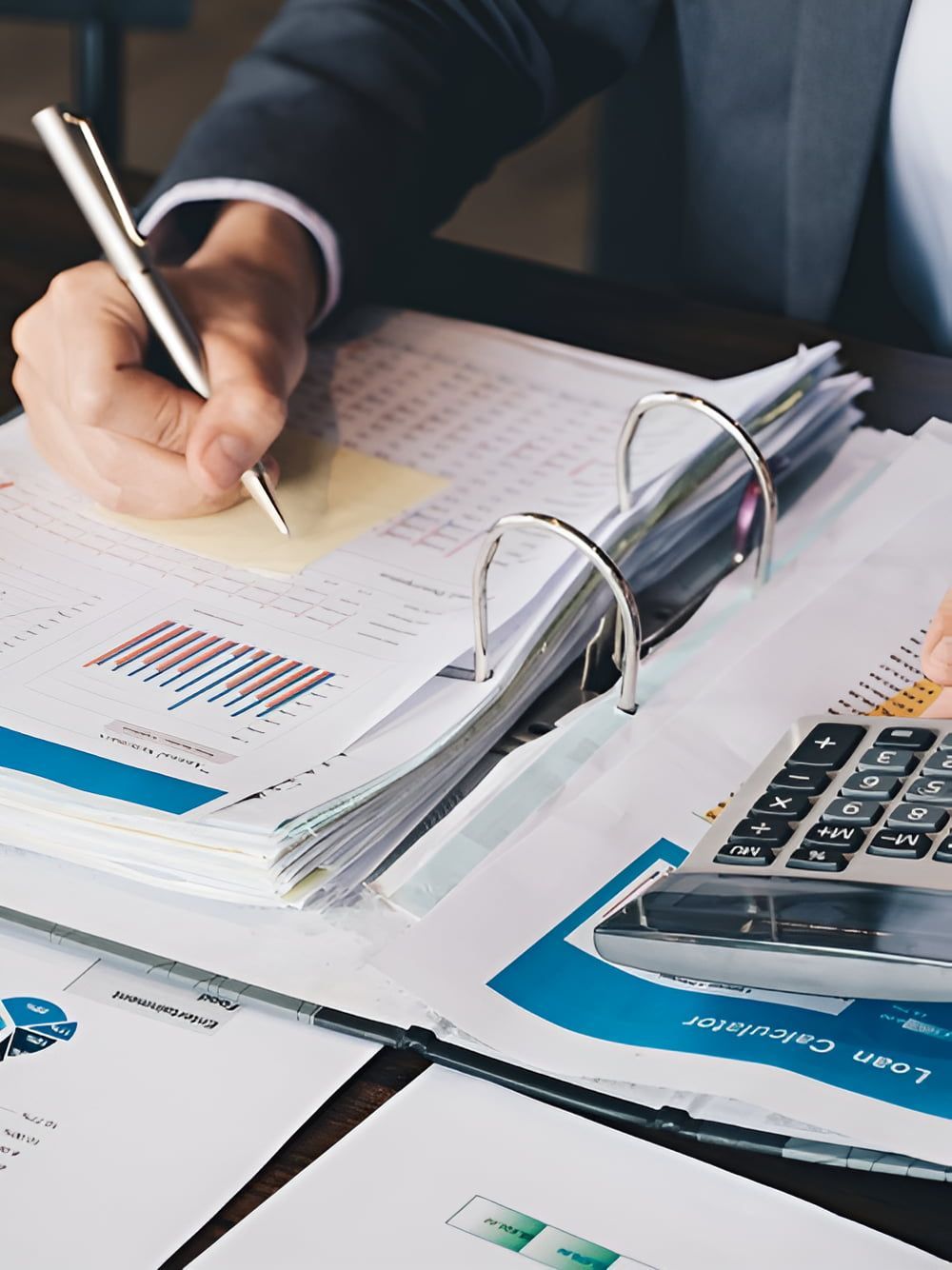 A Man is Writing on a Piece of Paper Next to a Calculator — AJA Bookkeeping Services In Cairns, QLD