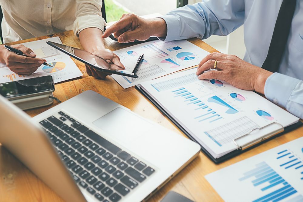 Two People Are Sitting at a Table With a Laptop and a Tablet — AJA Bookkeeping Services In Cairns, QLD
