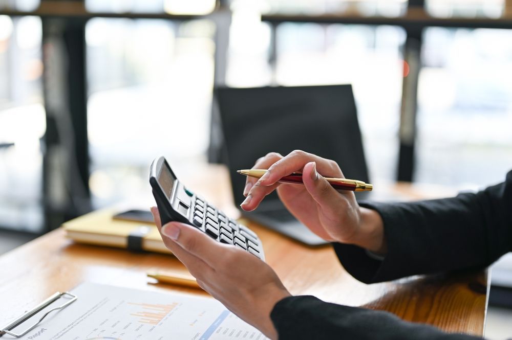 Person in Suit Calculating With Calculator, Pen in Hand — AJA Bookkeeping Services In Mareeba, QLD