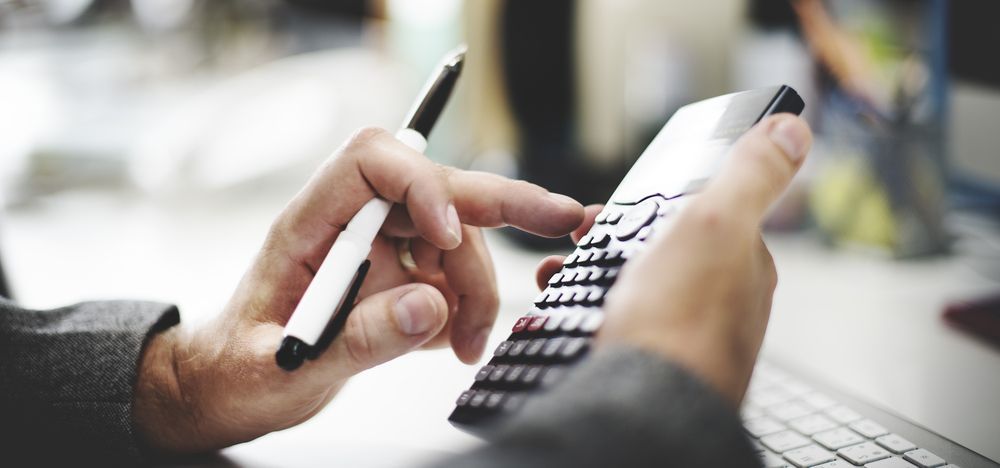 Person Using a Calculator and Holding a Pen, Likely for Financial Calculations — AJA Bookkeeping Services In Karumba, QLD