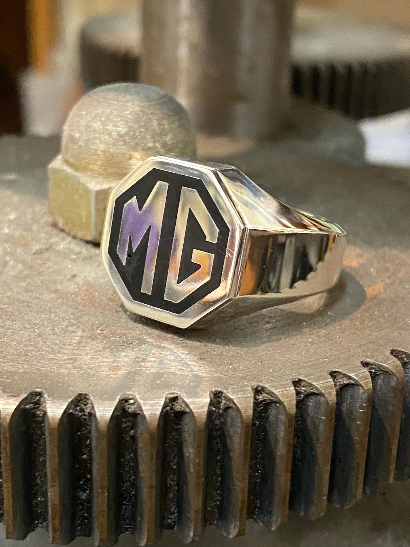A silver ring featuring an octagonal black-and-silver MG logo— Burchell's Jewellers In Bowral, NSW