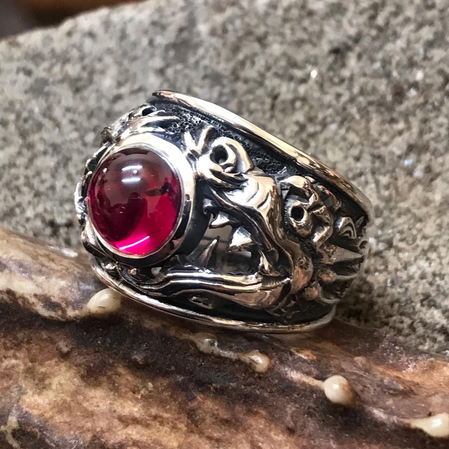 A silver ring with intricate, carved patterns featuring a central, polished, deep red round gemstone, set on a rock — Burchell's Jewellers In Bowral, NSW