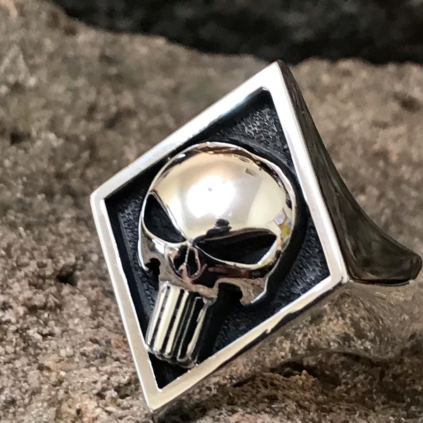 A silver ring featuring a polished Punisher skull logo set against a textured black diamond-shaped background — Burchell's Jewellers In Bowral, NSW