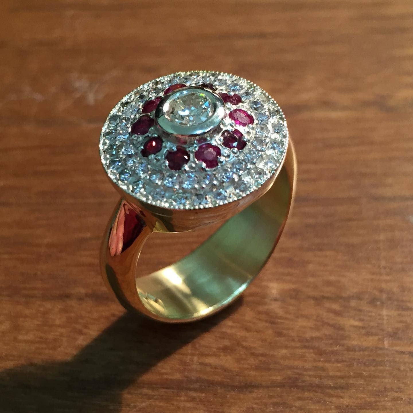 Gold ring with a central diamond, surrounded by rubies and smaller diamonds on a circular setting. — Burchell's Jewellers In Bowral, NSW