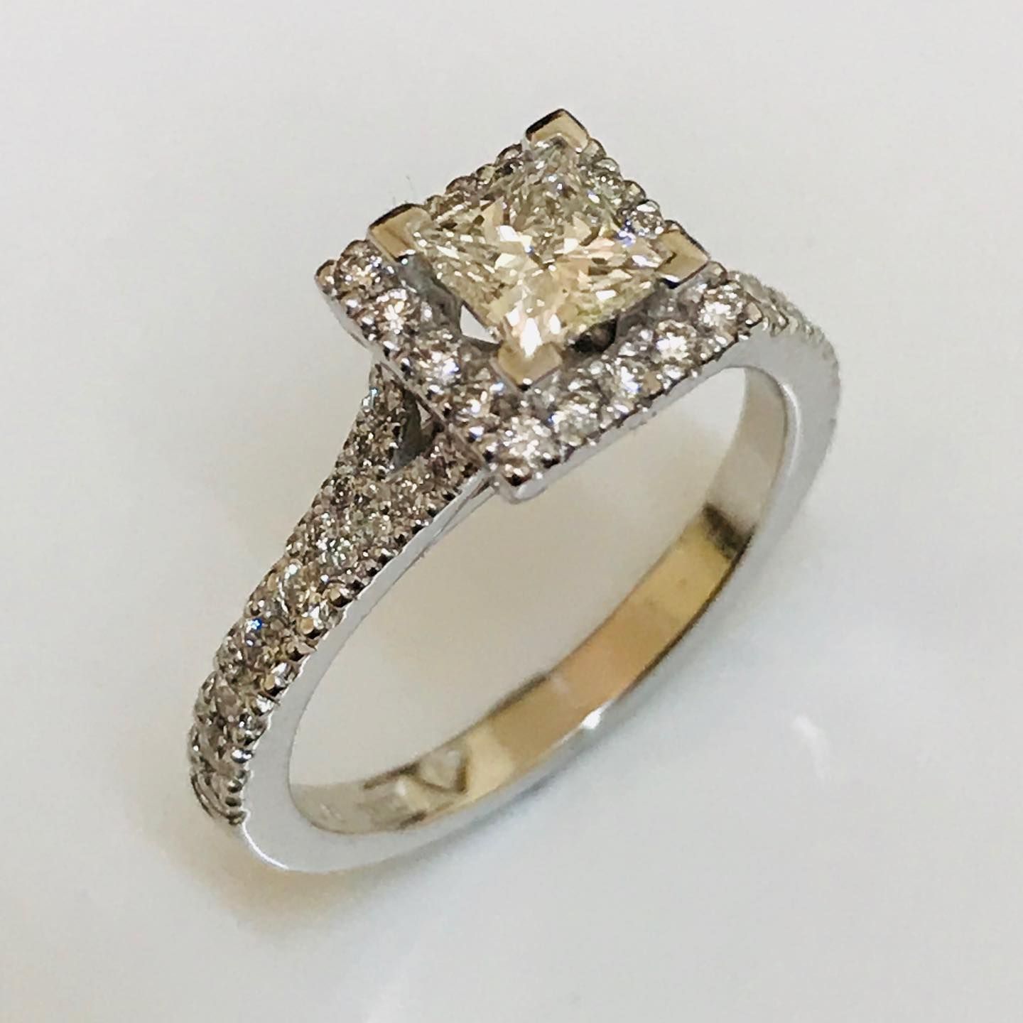 A silver diamond engagement ring with a princess-cut center stone surrounded by a halo, set on a pavé diamond band.  — Burchell's Jewellers In Bowral, NSW