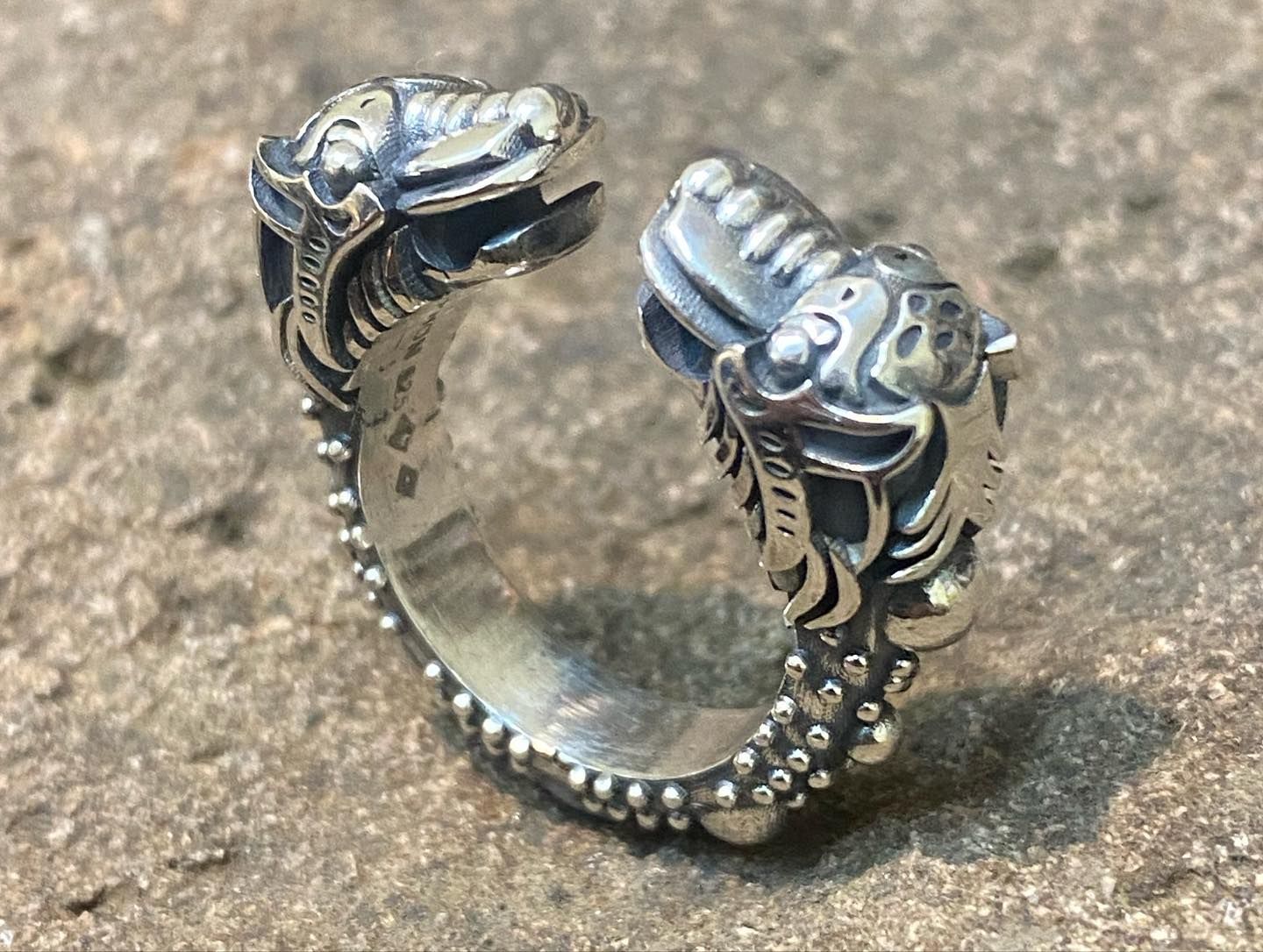 A silver open-ended ring featuring two detailed, snarling wolf or dragon heads facing each other, set on a textured band. — Burchell's Jewellers In Bowral, NSW