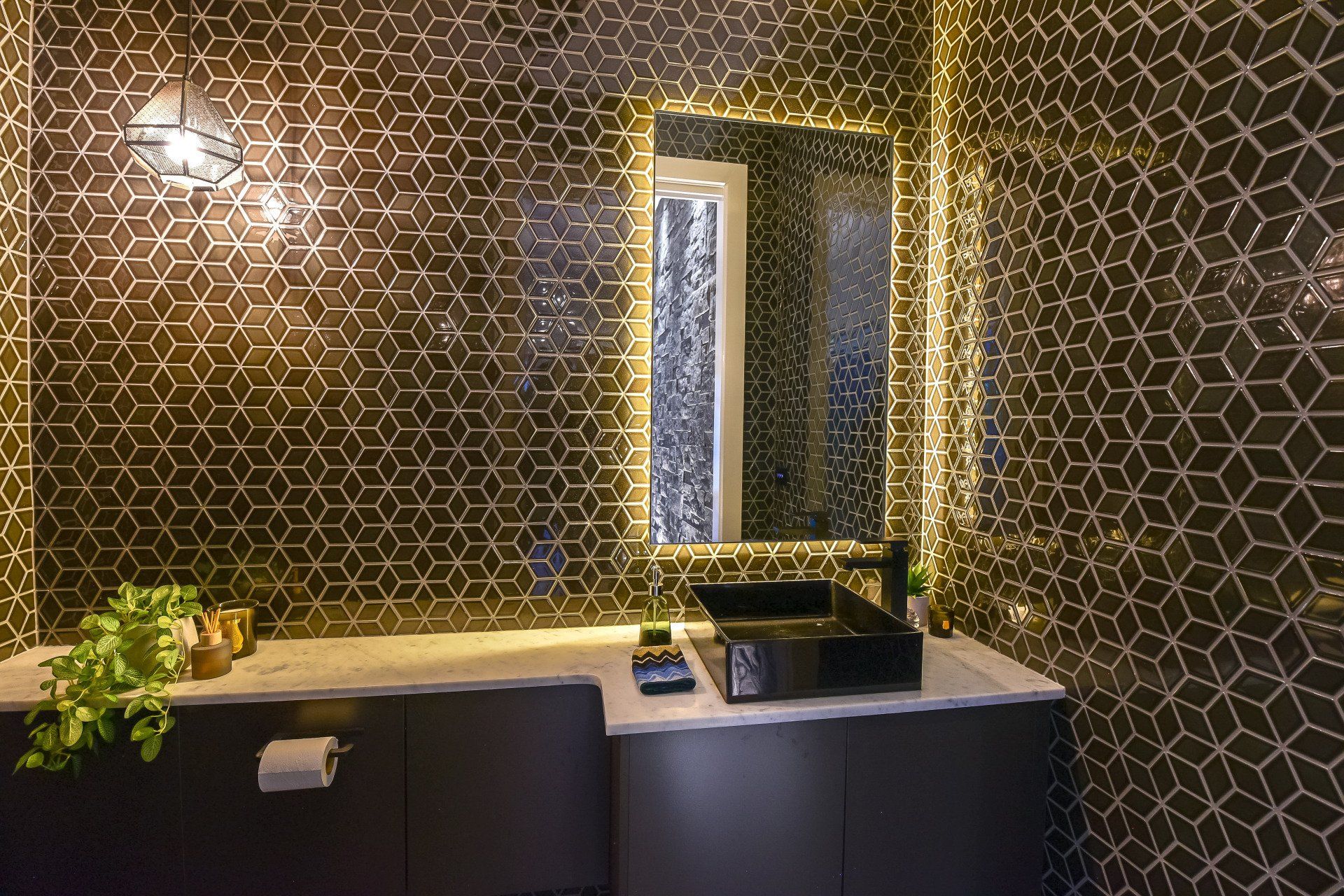A bathroom with a sink , mirror , and black tiles.
