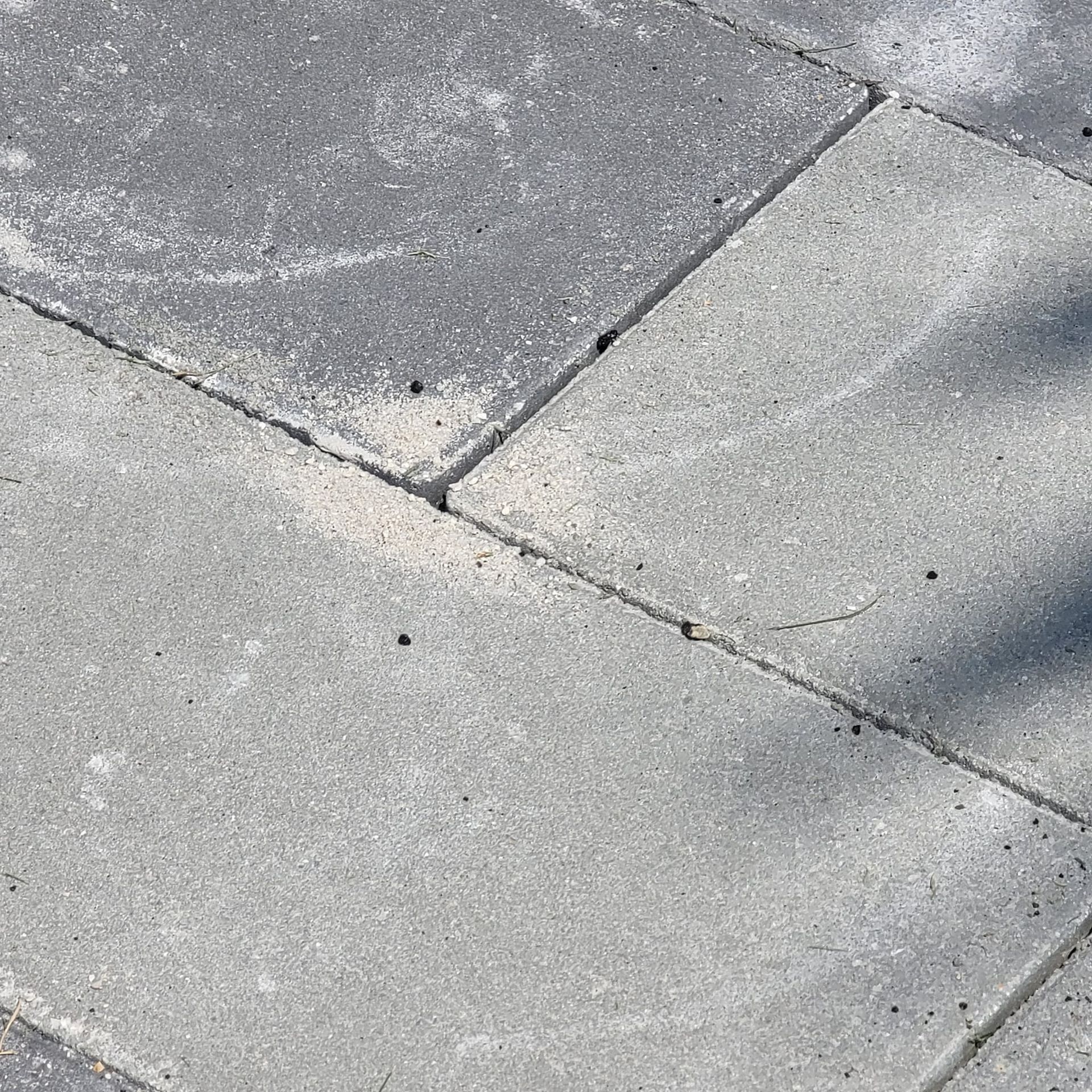 Close-up of rectangular grey concrete paving stones arranged in a running bond pattern with visible joints.