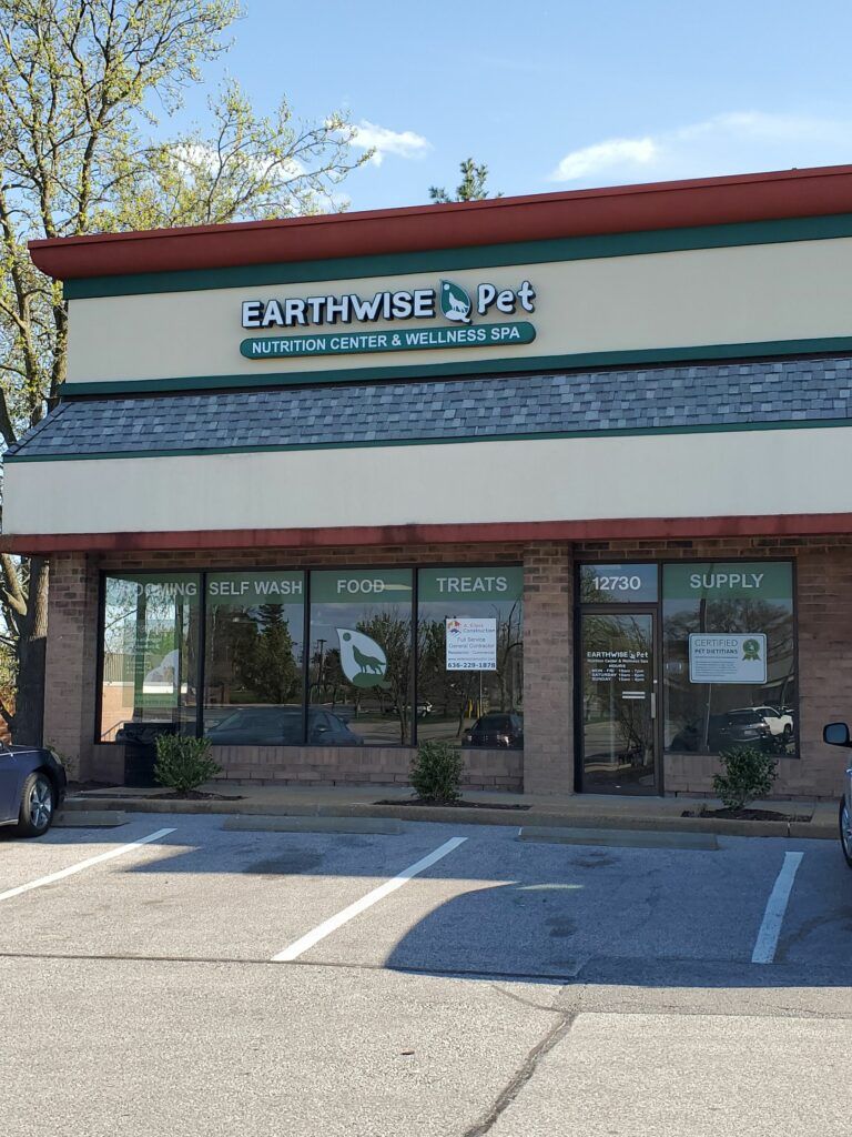 An Earthwise Pet store exterior with cream and green trim and signage in a parking lot.