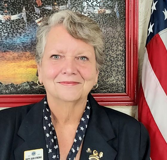 A woman standing in front of an american flag and a puzzle