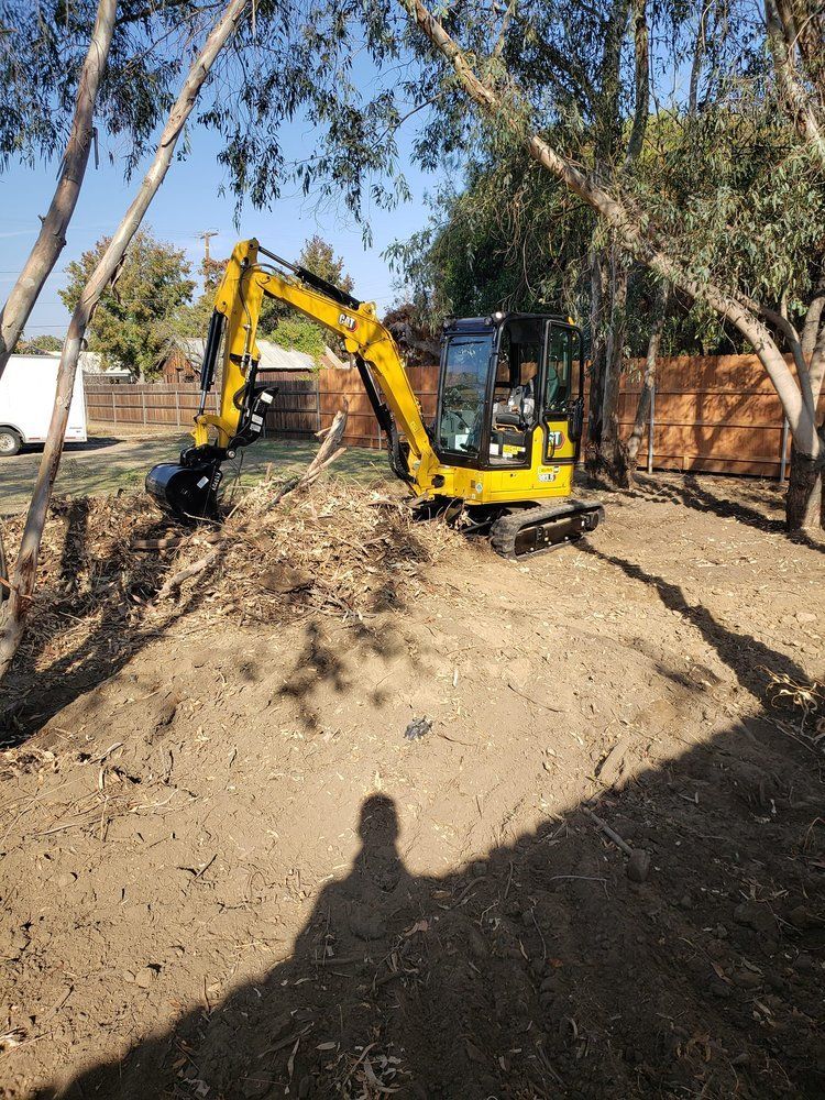A yellow excavator is digging a hole in a dirt field.