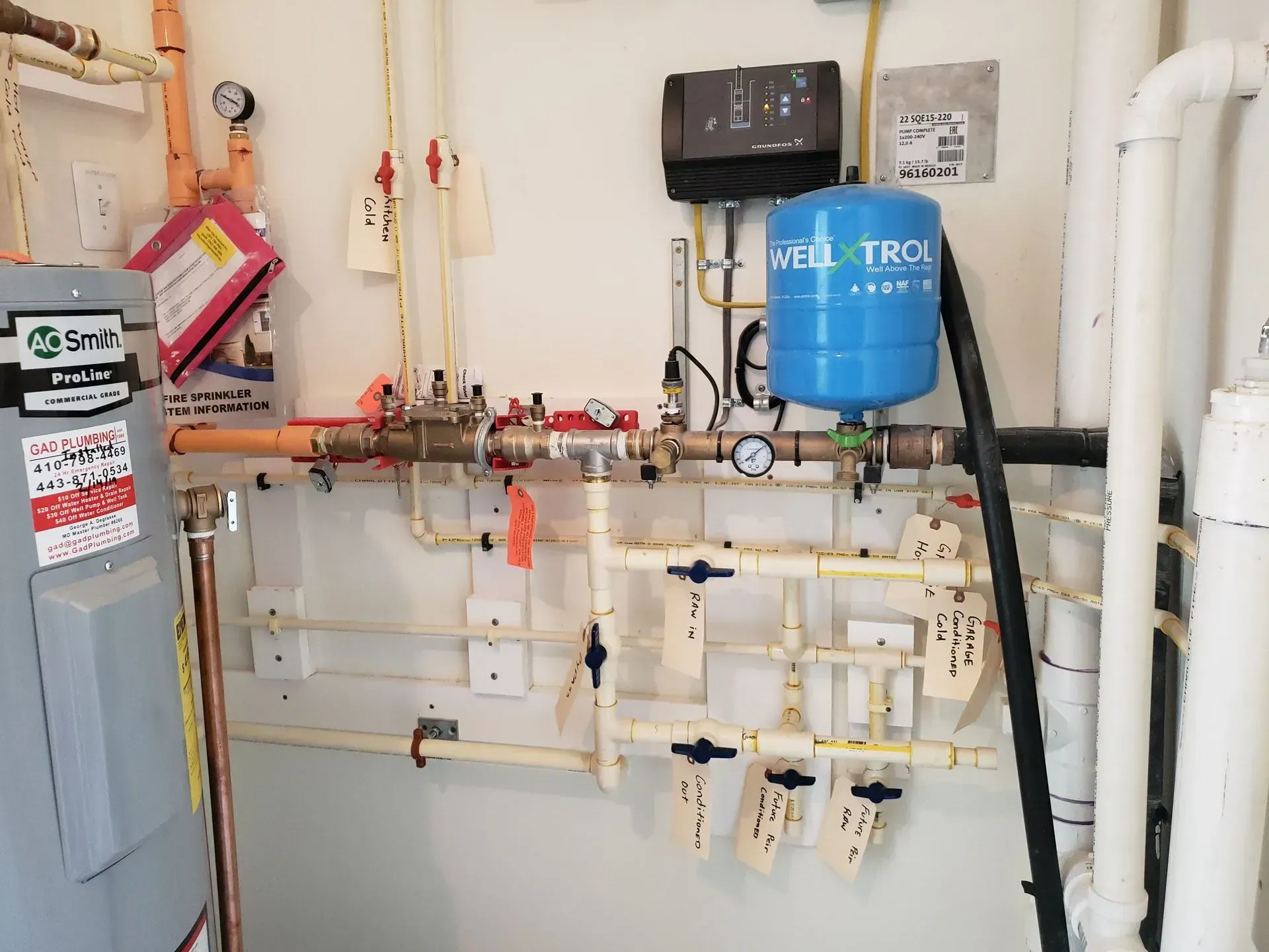 Utility room with water filtration pipes, valves, and a blue tank mounted on a wall