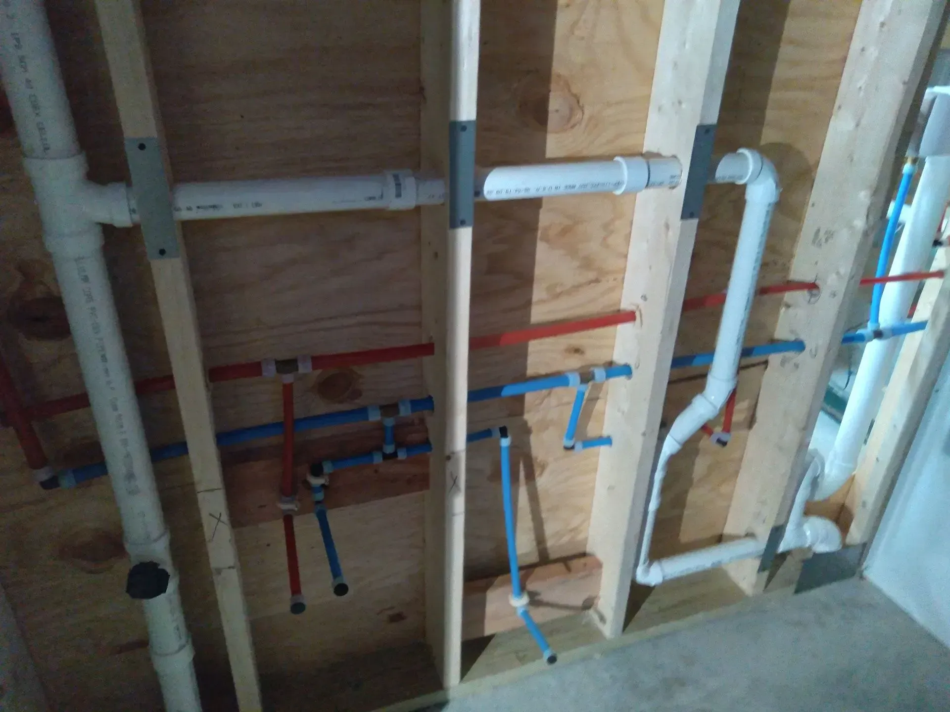 Framed wall with exposed plumbing pipes and valves under construction