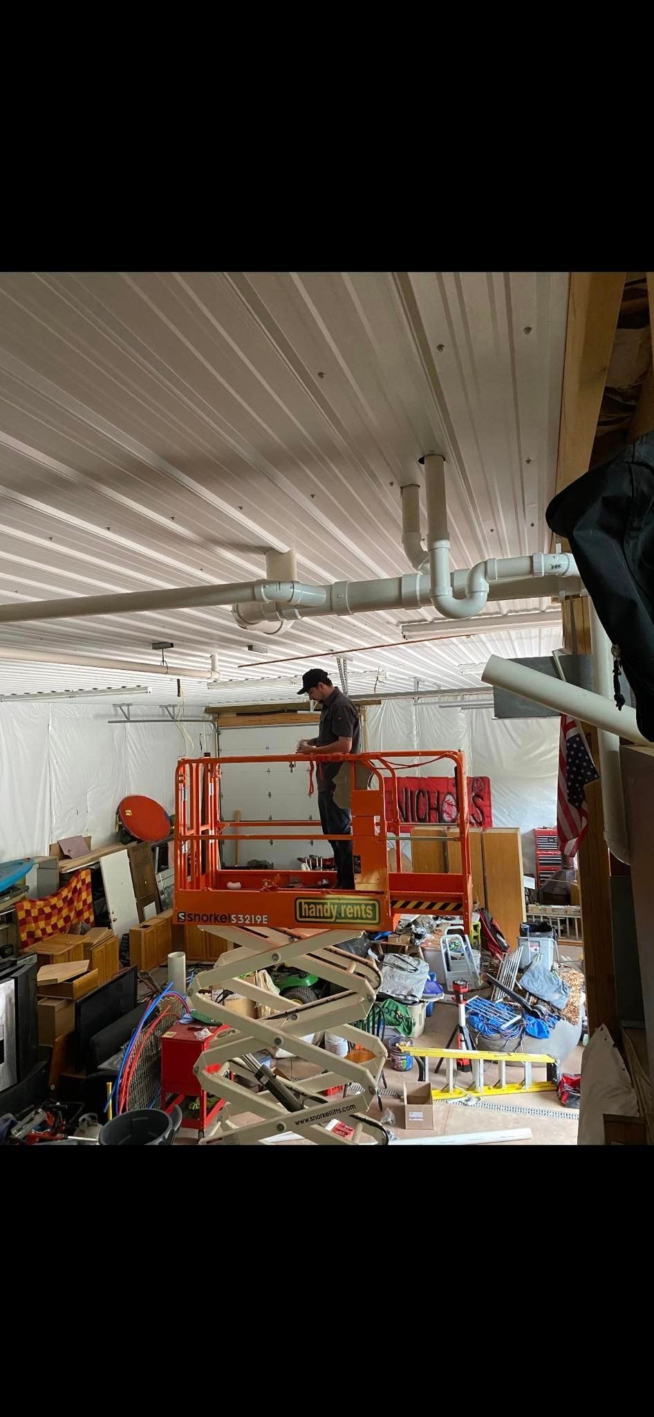 A man is standing on a lift in a messy room.