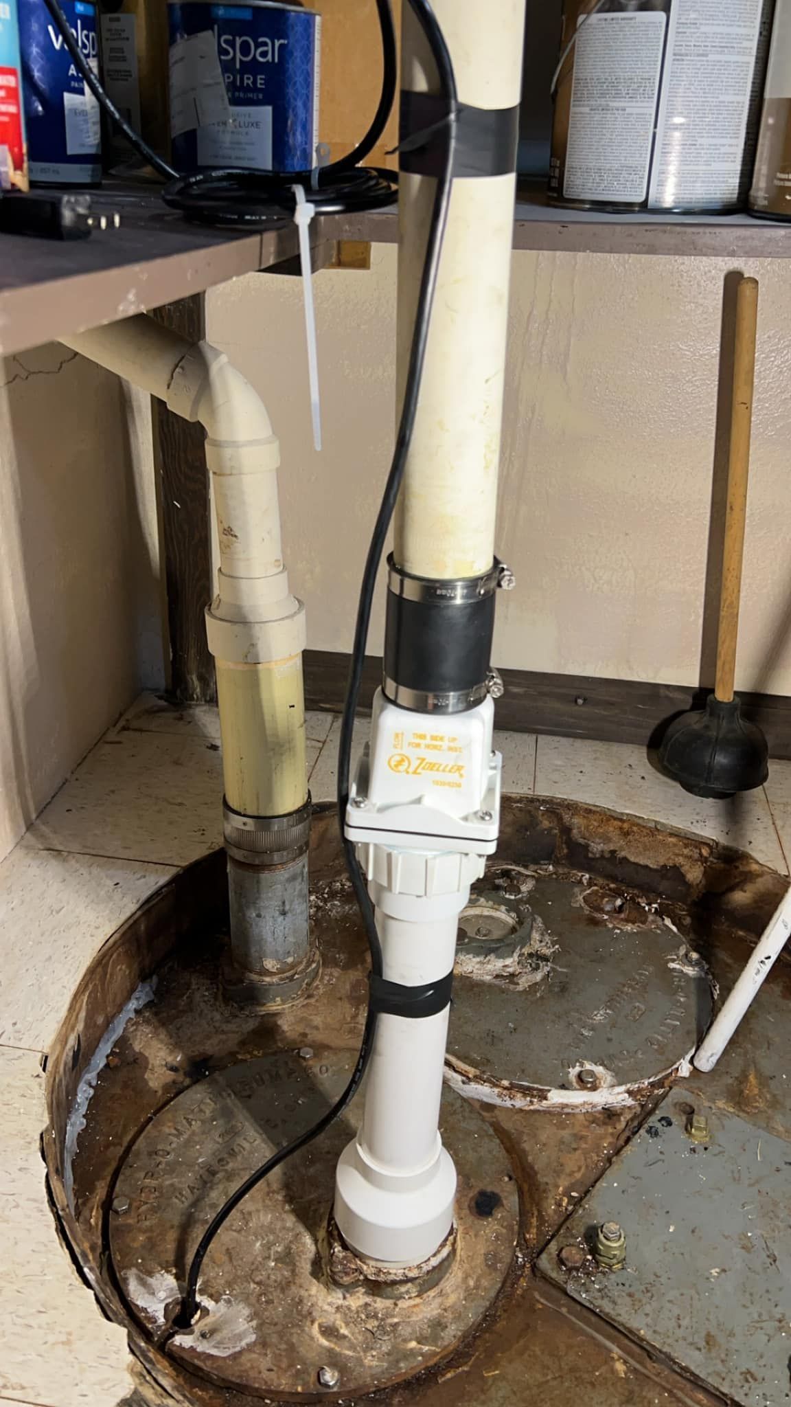 A basement drain with a pump attached to it.