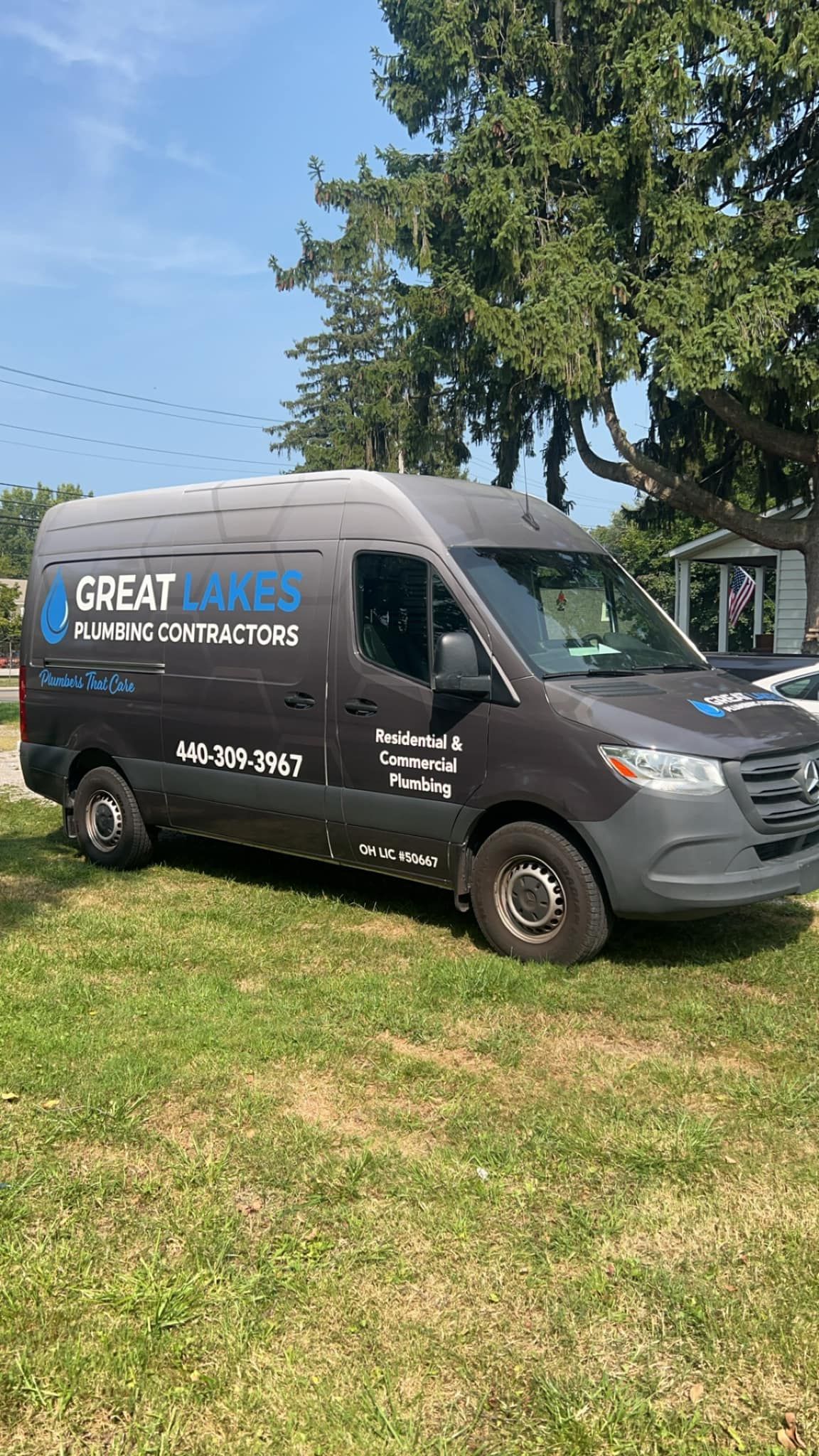 A black van is parked in a grassy field.