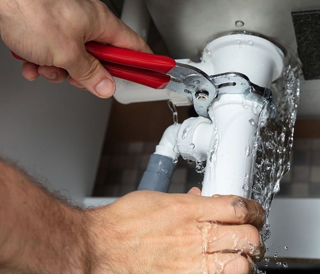 A person is fixing a sink with a pair of pliers.