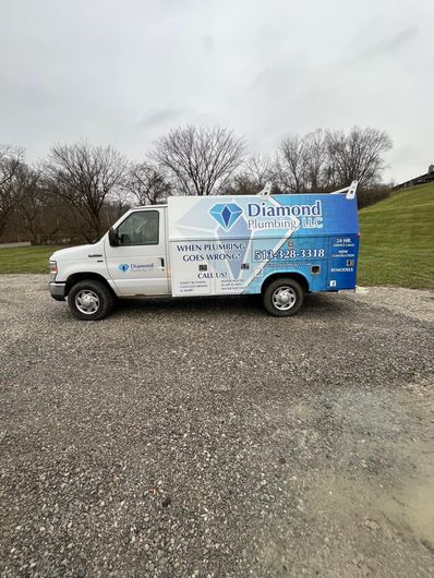 A white and blue van is parked in a gravel lot.
