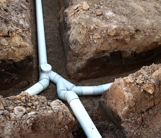 Three white pipes are connected to each other in the dirt