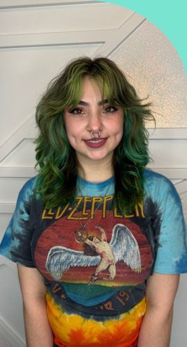 A woman with green hair is wearing a led zeppelin t-shirt.