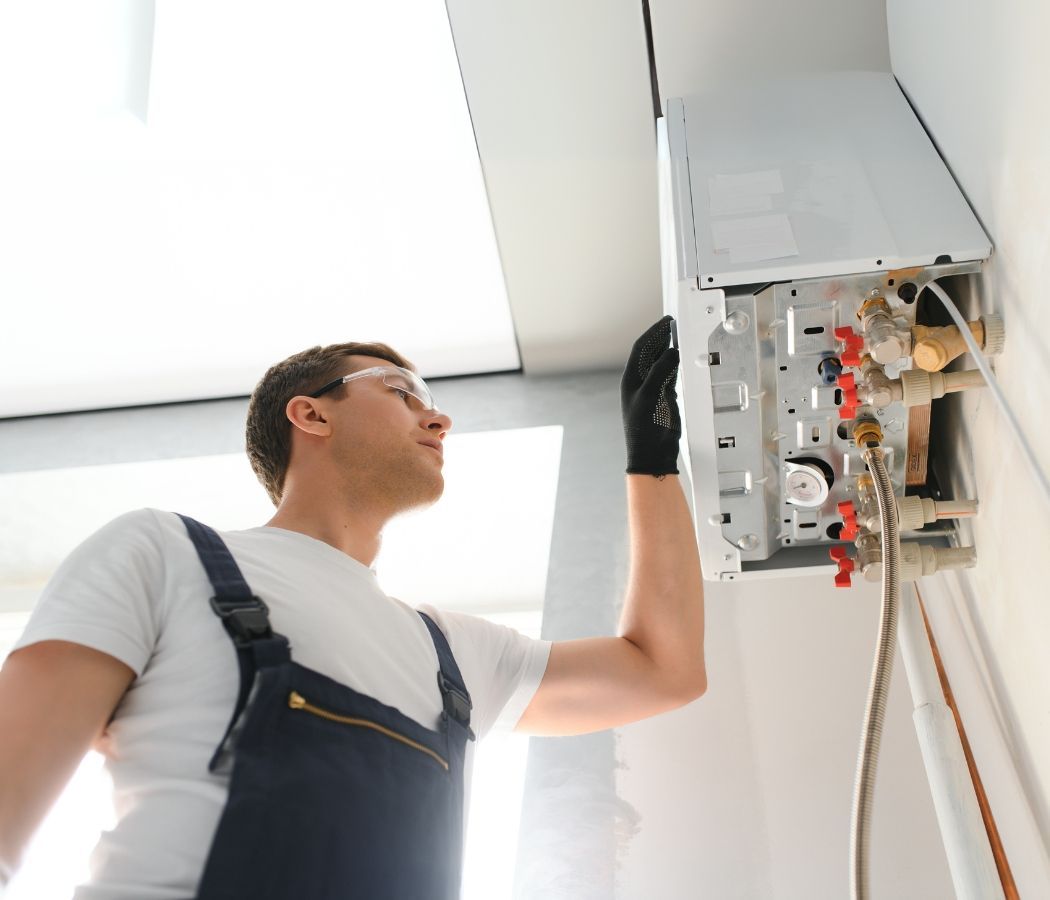 A man in blue overalls is working on a boiler