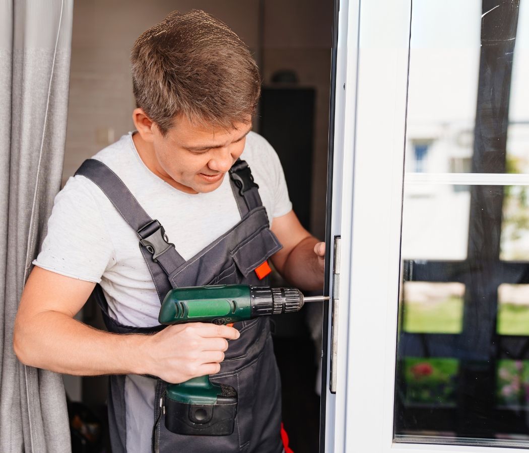A man is using a drill to fix a door.