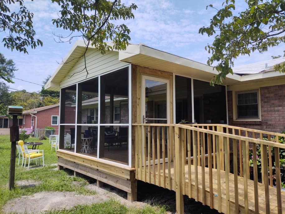 Screened porch with ramp attached to a brick building, on a sunny day.