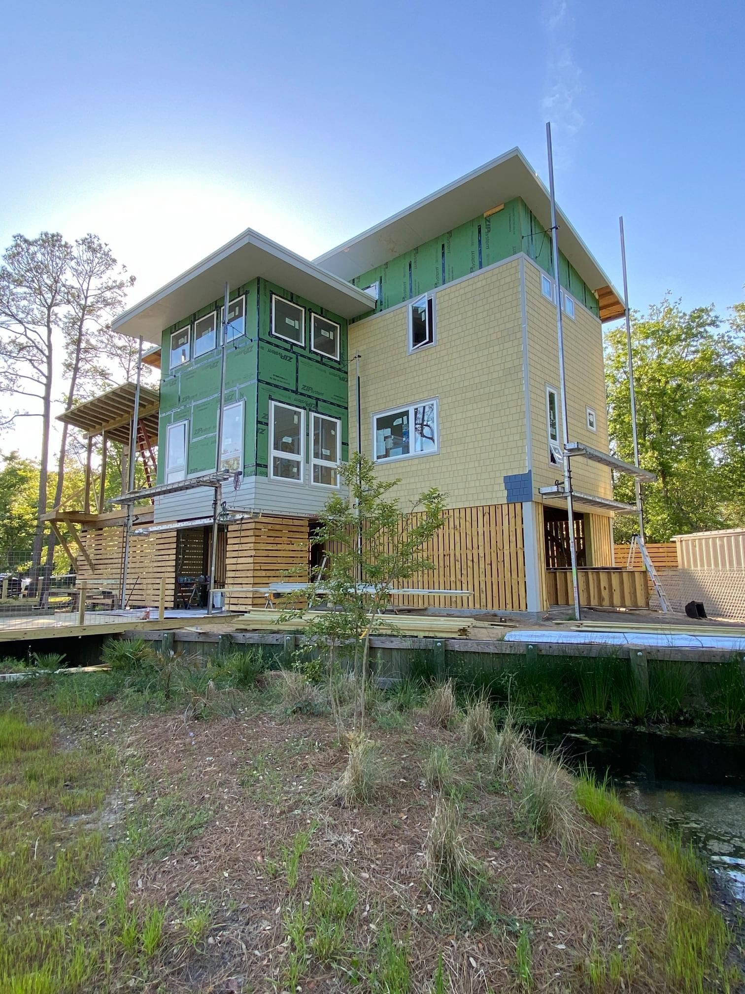 A large house is being built next to a body of water.