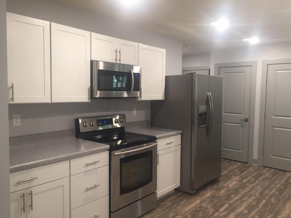 Modern kitchen with white cabinets, stainless steel appliances, and gray countertops.