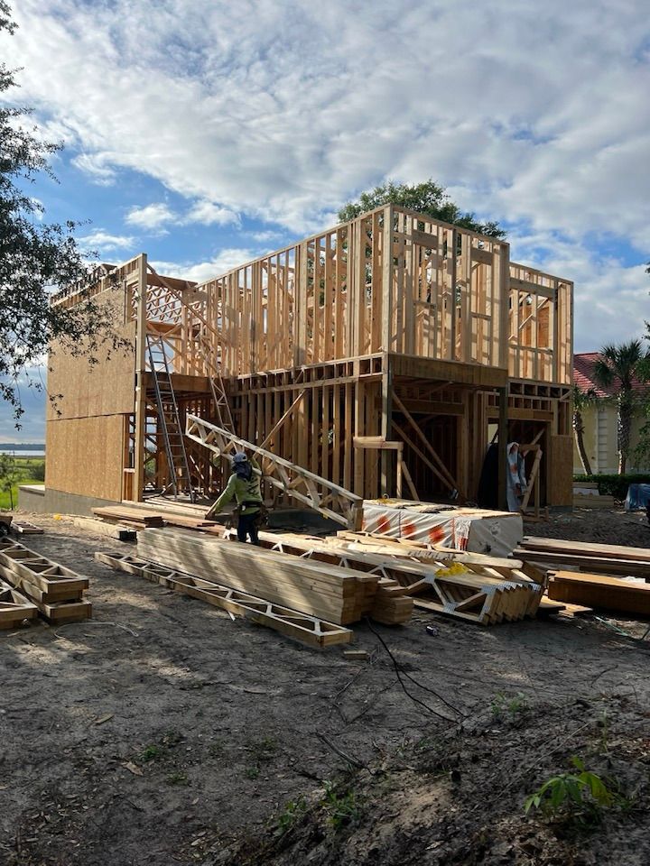 A large wooden house is being built in the middle of a dirt field.