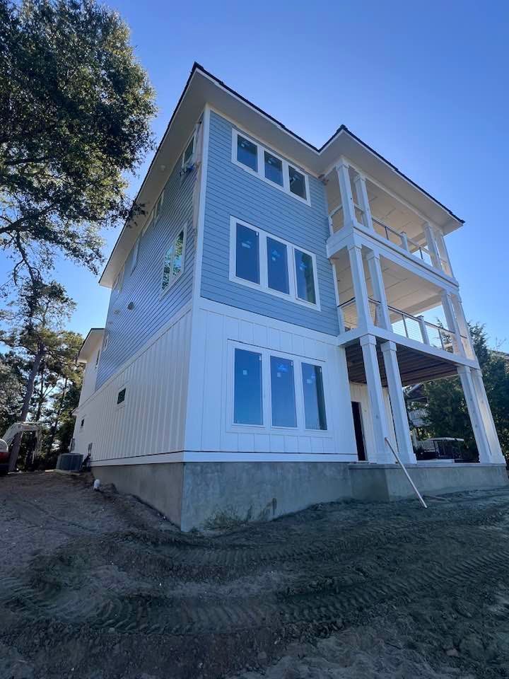 A large blue and white house with a lot of windows is sitting on top of a hill.