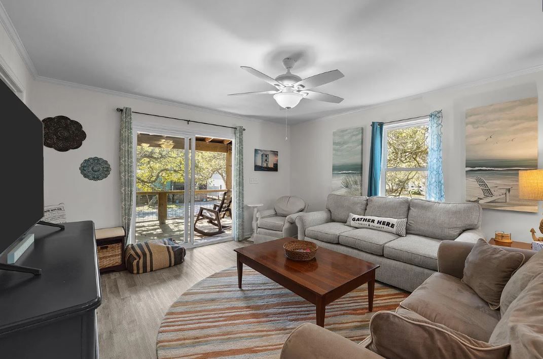 Cozy living room with a gray sectional sofa, coffee table, and sliding glass doors leading to a deck.