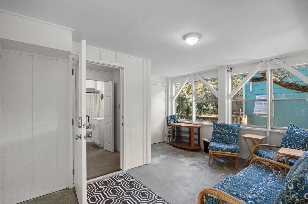 Sunroom with blue patterned furniture, large windows, and a doorway.