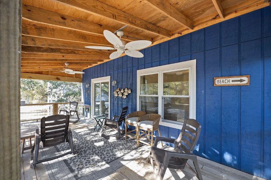 Covered porch with blue walls, ceiling fans, and outdoor furniture.