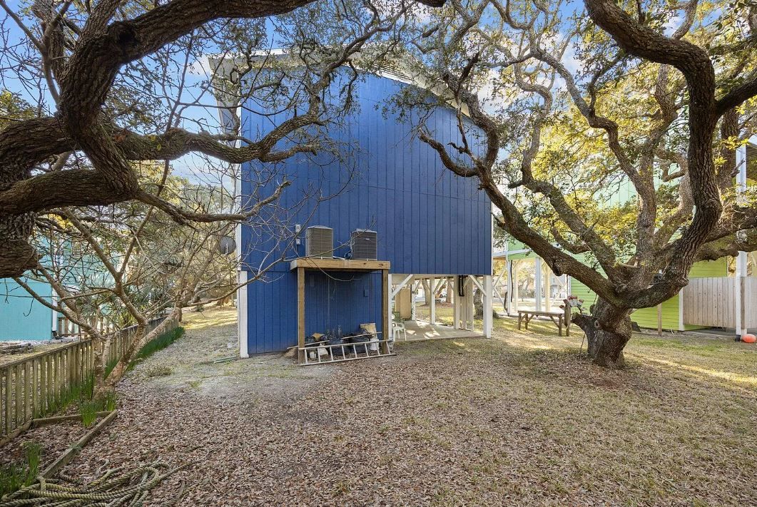 Blue elevated house with tree branches framing the view.