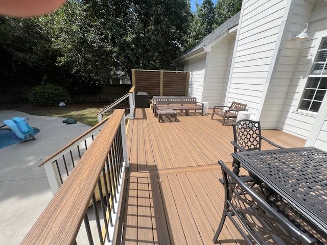 Wooden deck with outdoor furniture next to a light-colored house.
