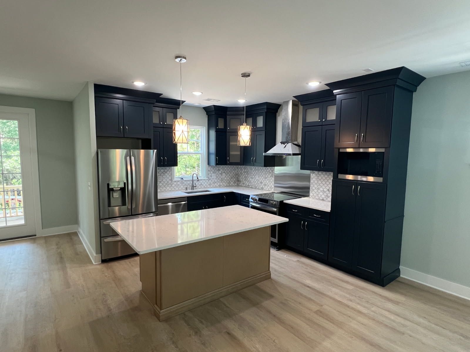 Modern kitchen with navy blue cabinets, stainless steel appliances, and a light-colored island.