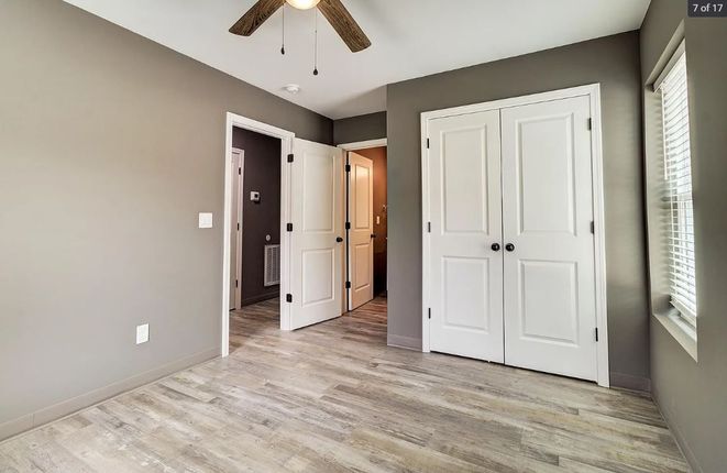 A bedroom with a ceiling fan and a closet.