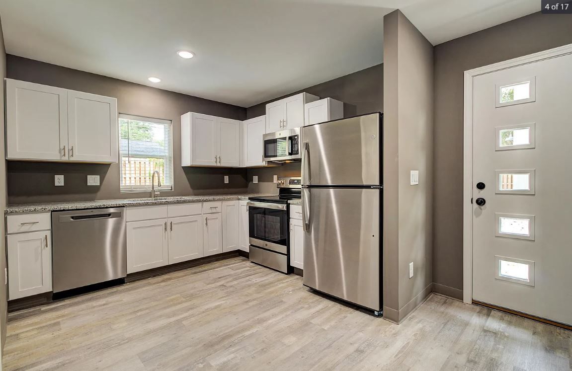 Kitchen with white cabinets, stainless steel appliances, and light gray flooring.