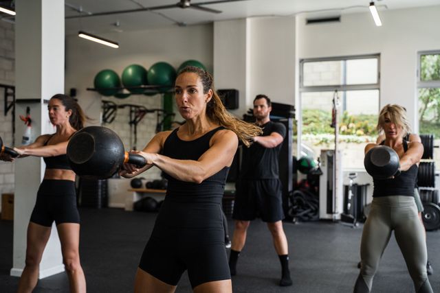 A group of people are doing kettlebell exercises in a gym.