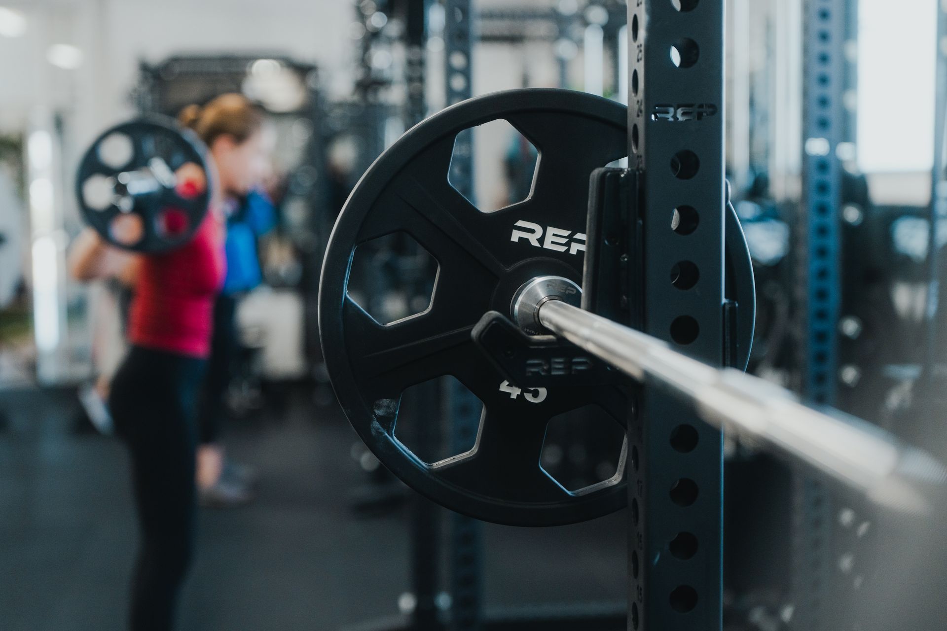 A man is lifting a barbell on a bench in a gym.