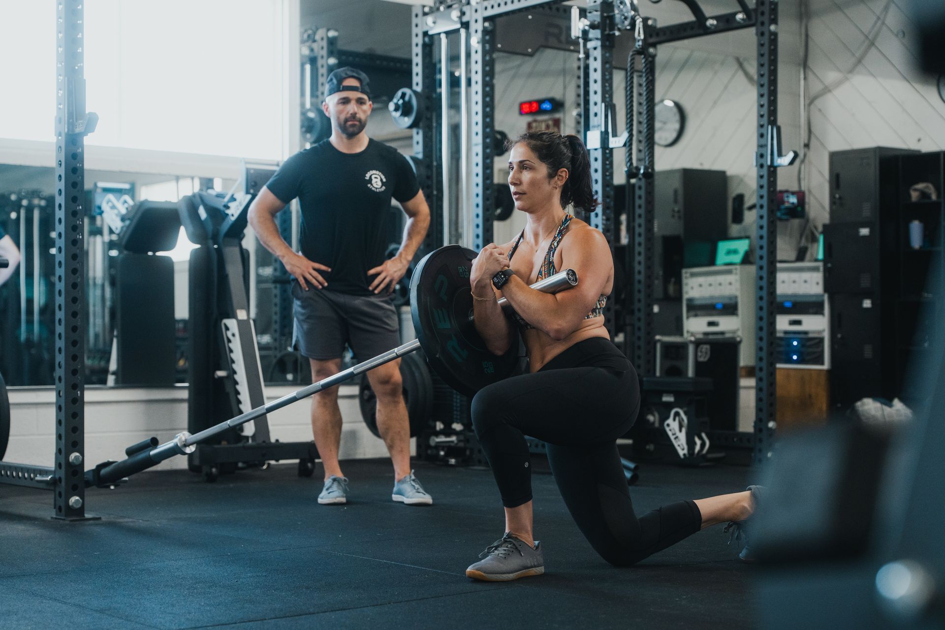 A man and a woman are lifting dumbbells in a gym.
